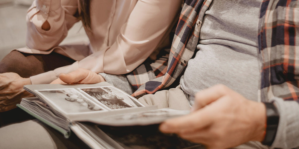 The hands of senior parents holding a photo album of old family photos.