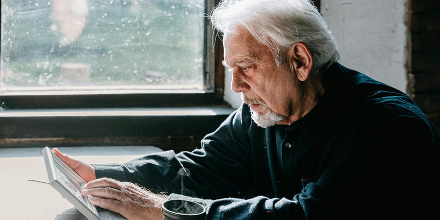 A grieving man stares at old photos wondering what to do with them in this time of bereavement
