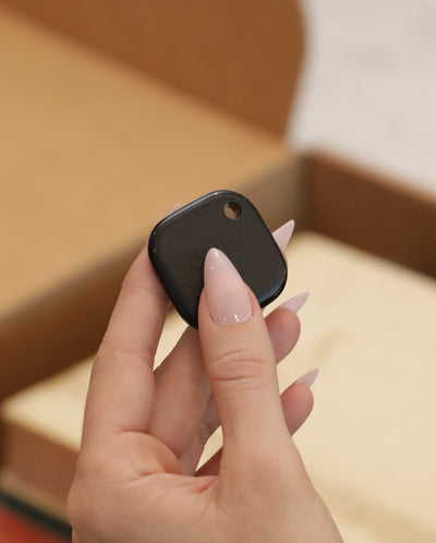 A hand holding the AirTracker device that ships in every box