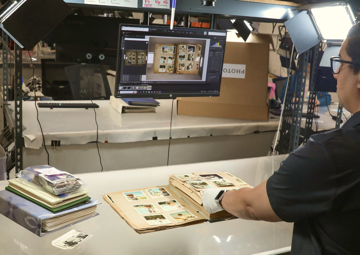 A Photokive archivist digitizing a vintage photo album at a professional lit copy station
