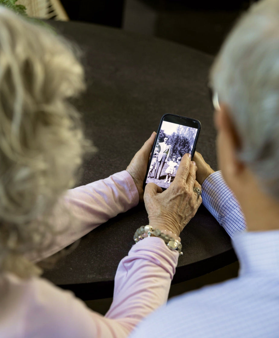An older couple looking at a restored black-and-white family photo on a phone