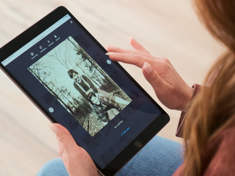 A woman viewing a restored family photo in the Photokive app on a tablet